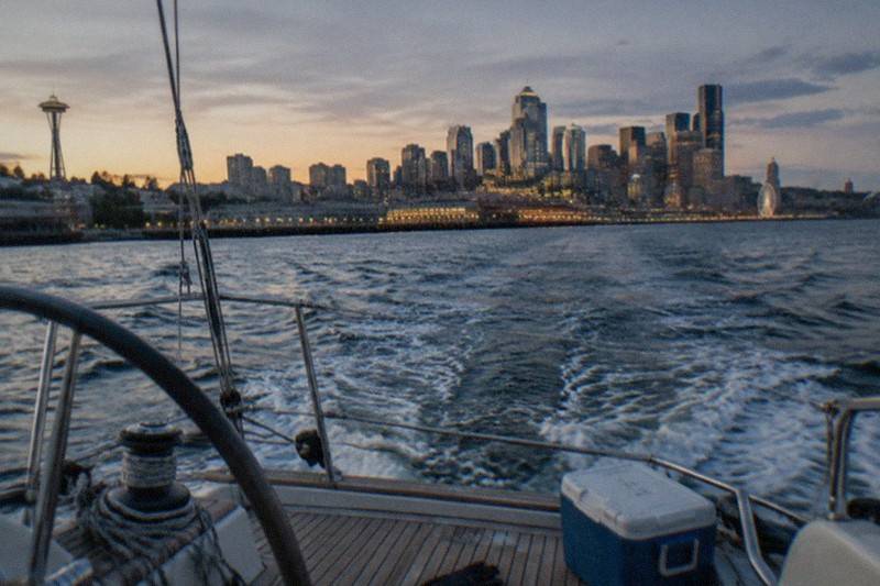 A 70ft sailboat heeling through sunset light on open water; Seattle's Original Sunset Sail, established 1984, is a BYOB trip of roughly two hours run by Sailing Seattle, from $71 per person, rated 4.9 across 232 reviews.