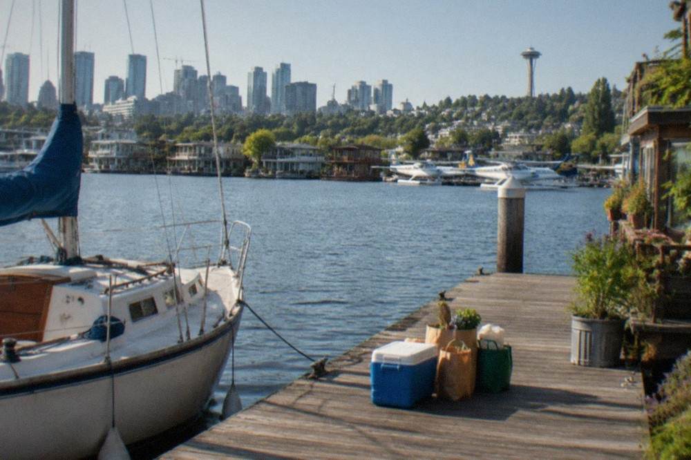Wooden dock on Lake Union with a sailboat moored beside picnic supplies and a cooler waiting to be carried aboard