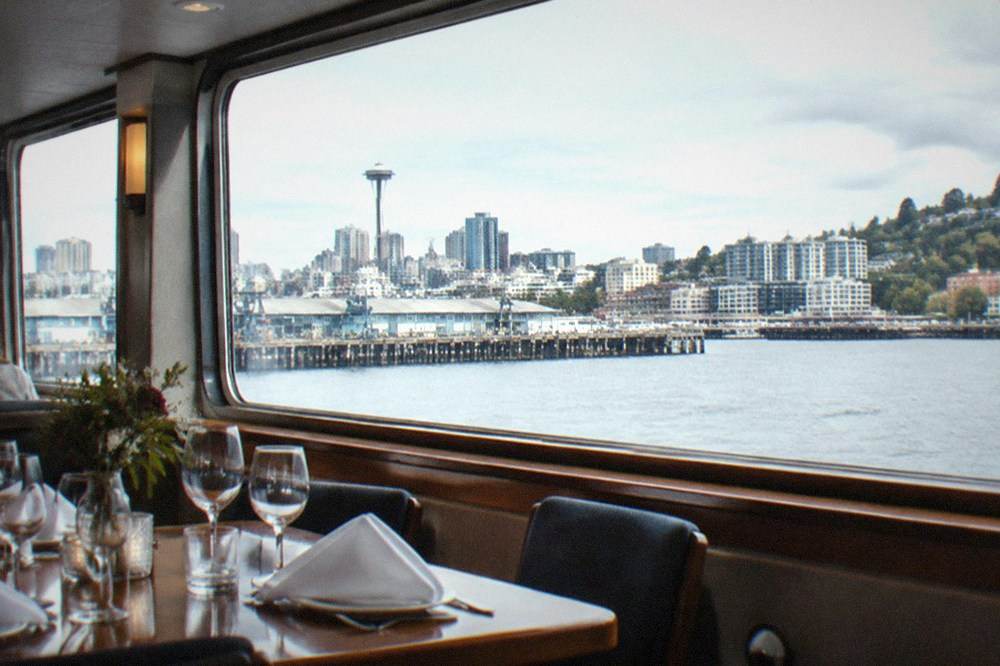 Set dinner table with glassware and place settings inside the climate-controlled salon of a lake cruise boat