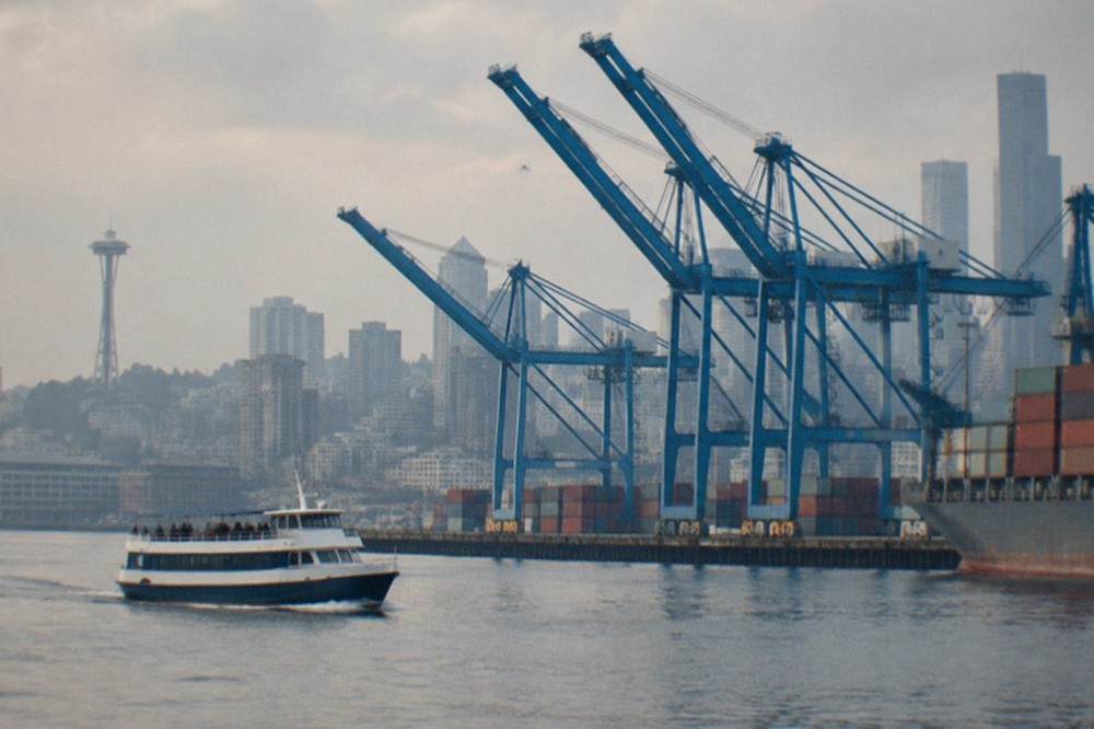 A harbor cruise boat on Elliott Bay with downtown Seattle office towers and the Space Needle rising behind it.