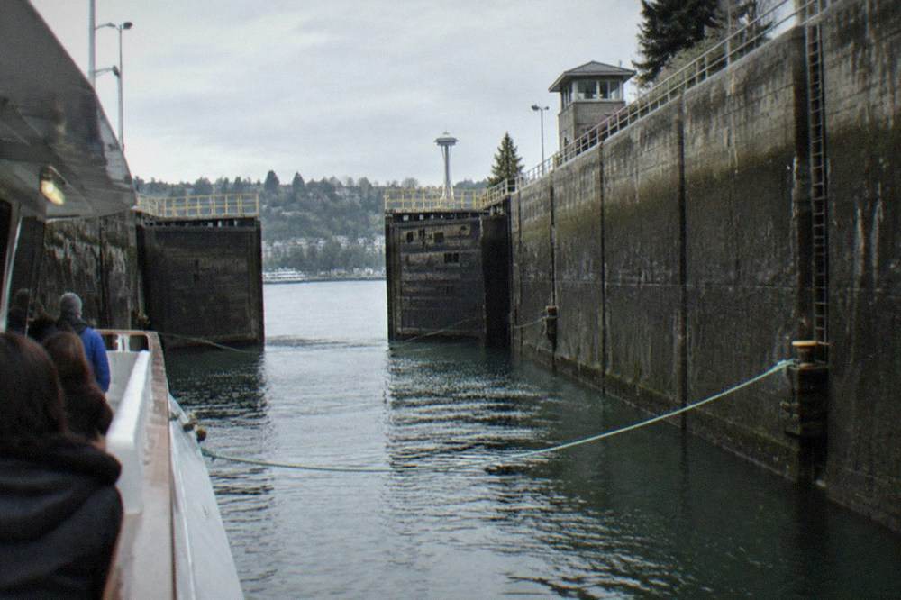 A passenger tour boat passing through a wide lock chamber with concrete gates on both sides