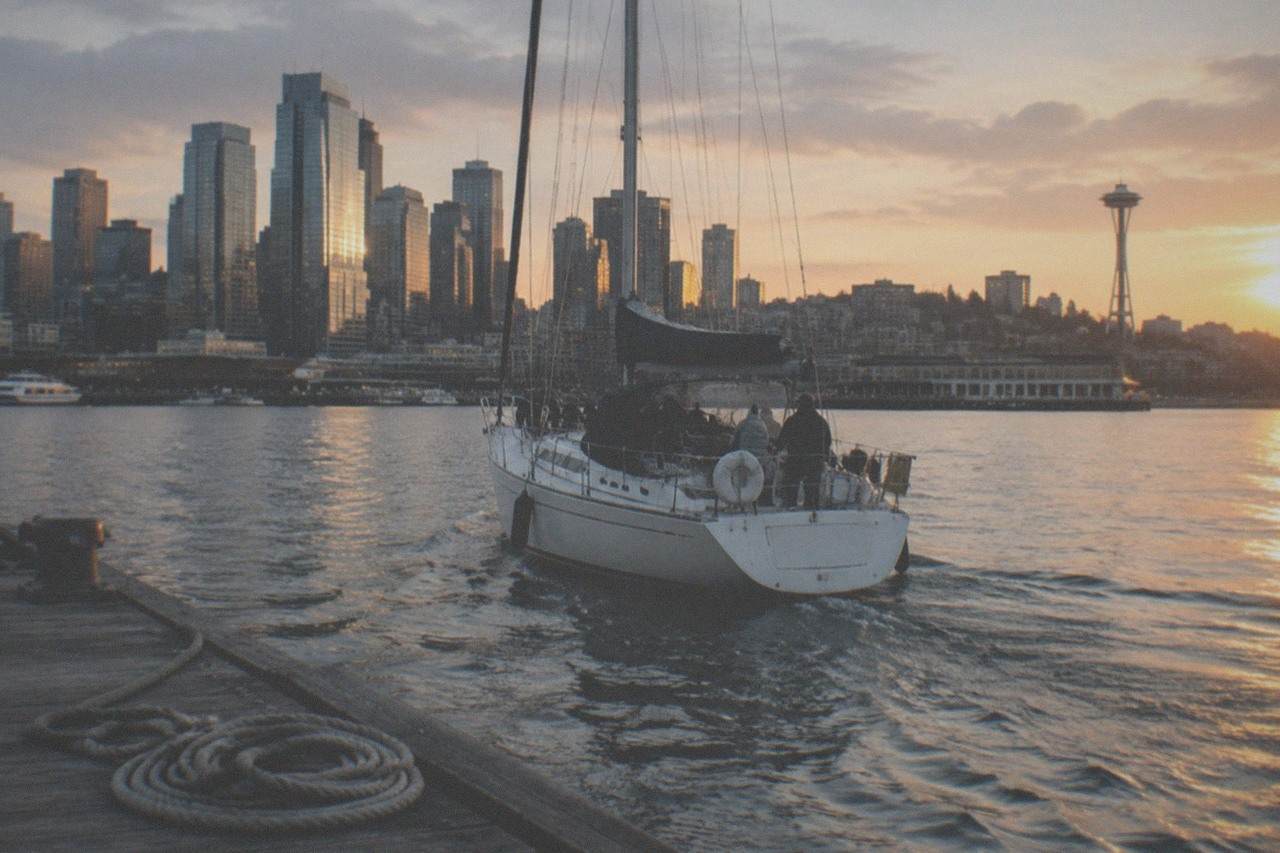 A Seattle waterfront pier with boats and the city skyline on a sunny summer evening.