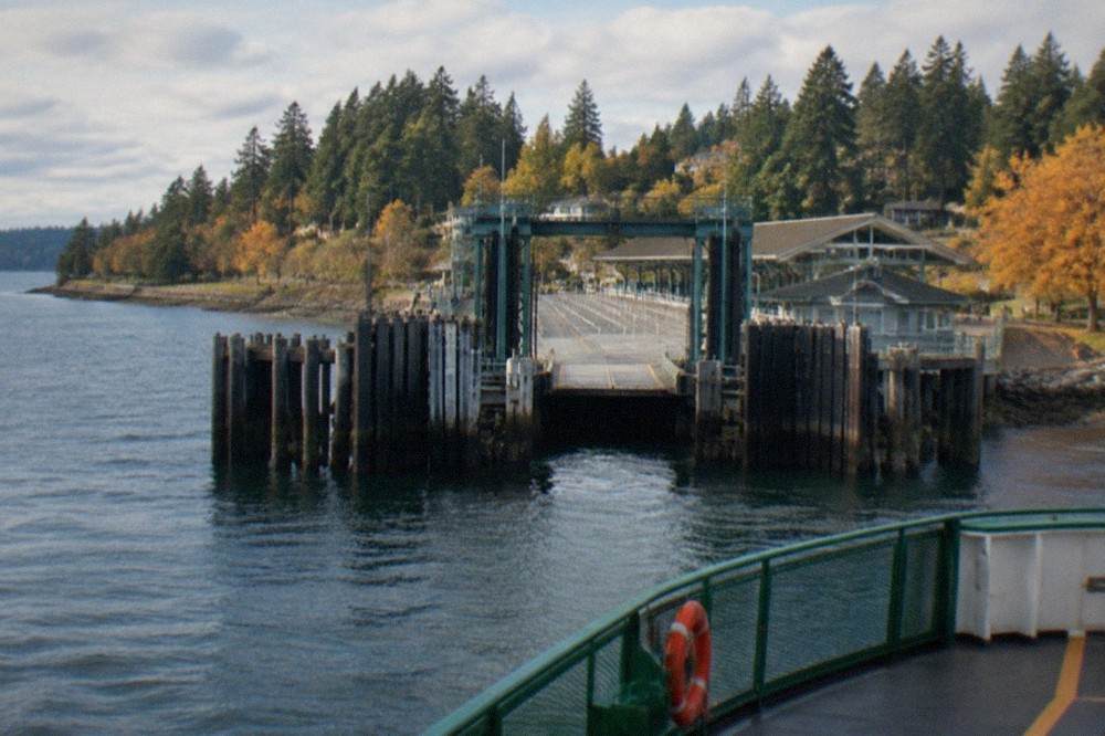 A Washington State ferry approaching the Bainbridge Island terminal across calm Puget Sound water
