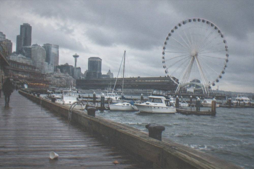 The Seattle waterfront promenade with moored boats and the Great Wheel in the background