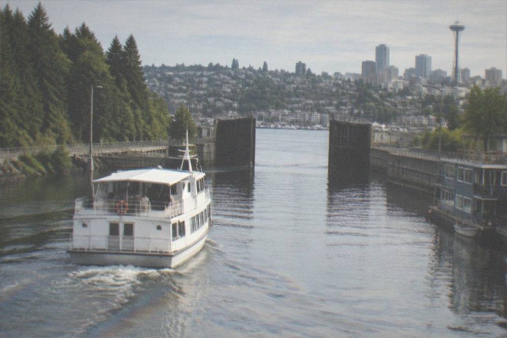 A passenger cruise boat cruising along a ship canal toward an open lock gate