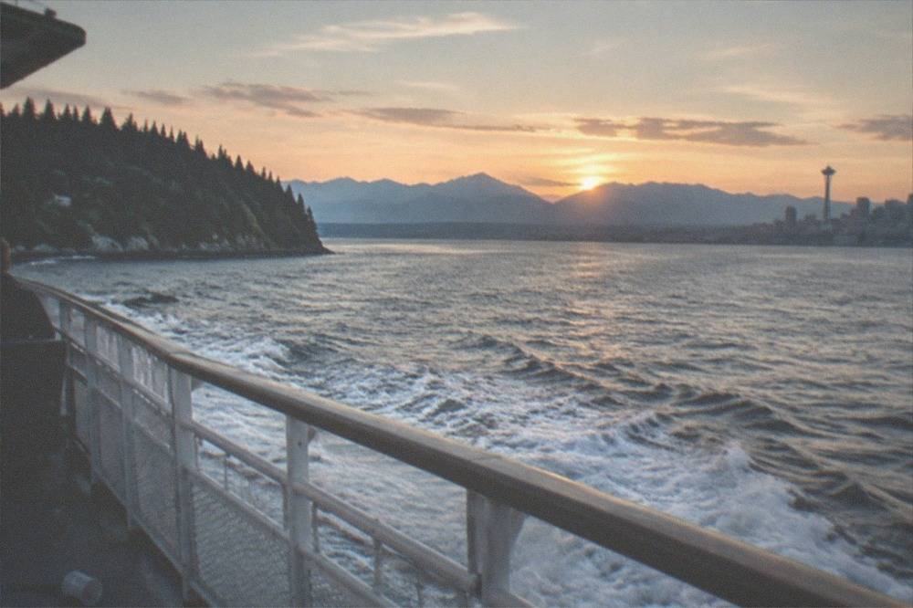A whale watching boat under wide evening light near Seattle's forested shoreline