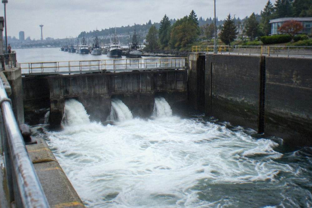 Water pouring through open lock gates as a chamber level equalizes with the canal beyond