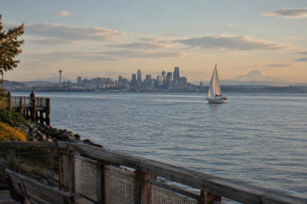 A sailboat on Elliott Bay in late afternoon light with the Olympic Mountains on the horizon