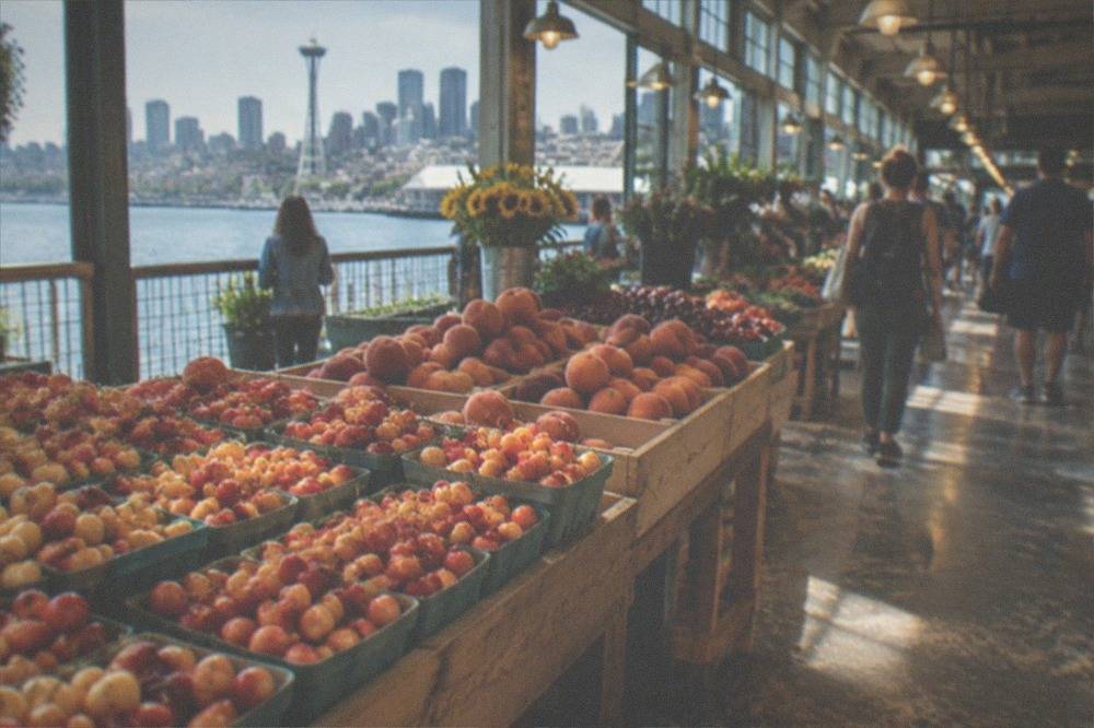 Public market arcade with produce stalls and crowds under an overhead sign