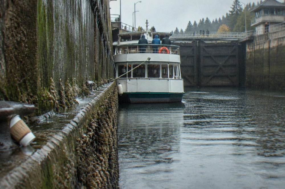 A tour boat tied up inside a large canal lock with gates closed behind it