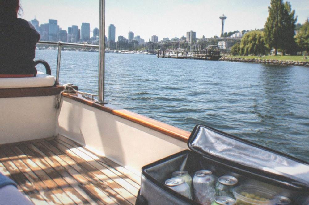 A soft cooler with drinks and snacks arranged on the wooden deck of a small charter boat
