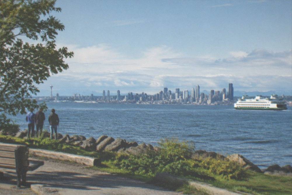 Passengers on a ferry deck watching the Seattle skyline recede across Puget Sound