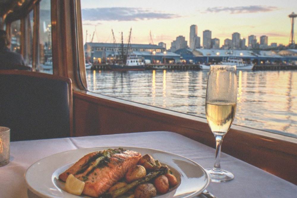 A plated salmon dinner and a glass of sparkling cider on a white tablecloth