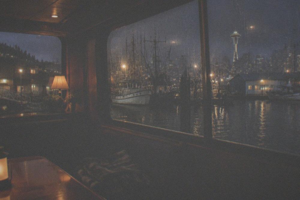 A covered boat salon with rain streaking the windows and warm interior lights