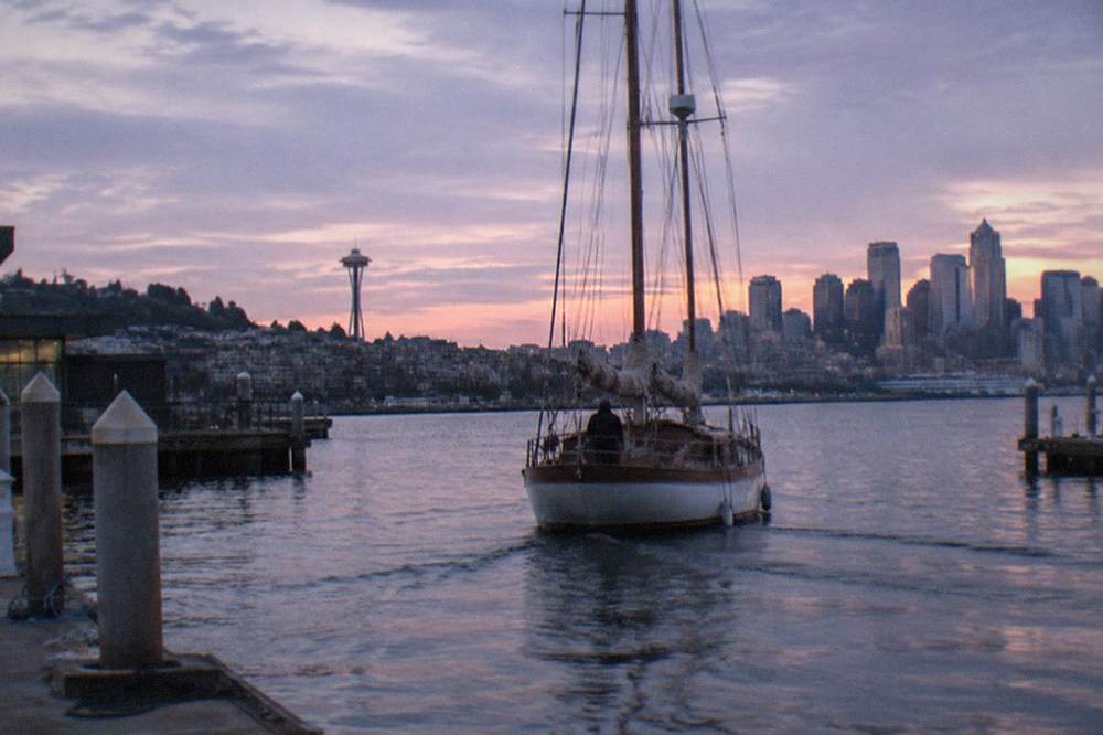 tall sailboat with raised masts crossing Elliott Bay at dusk
